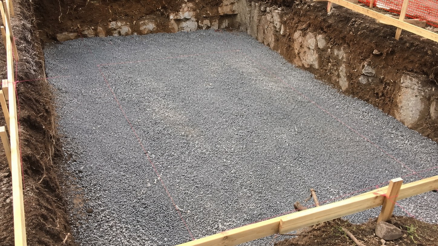 Pool excavation cut to grade with exposed ledge rock in the banks, compacted stone base and batter boards with string lines