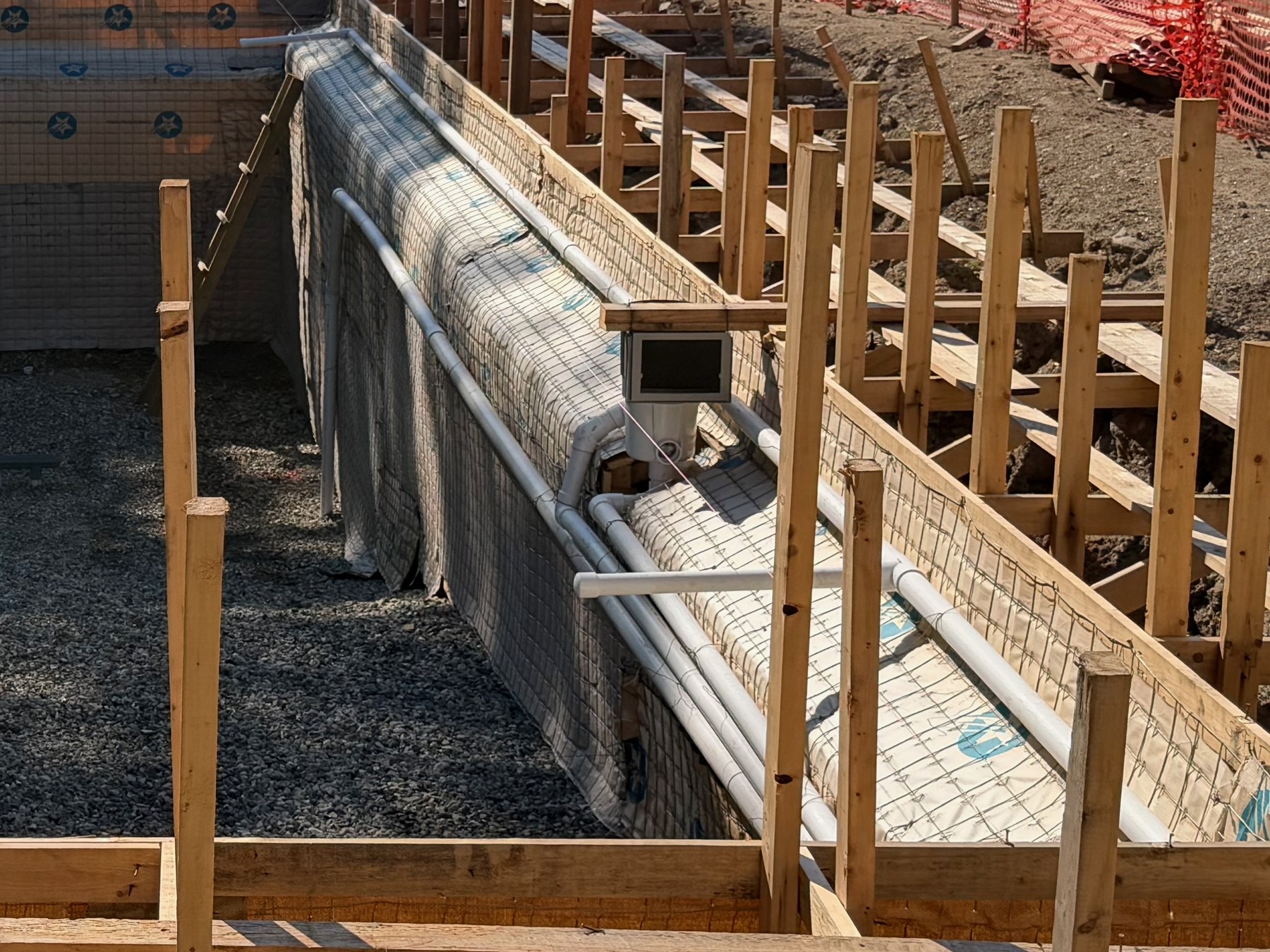 Reinforcing steel and rigid plumbing runs set against the formed wall of a gunite pool shell before placement