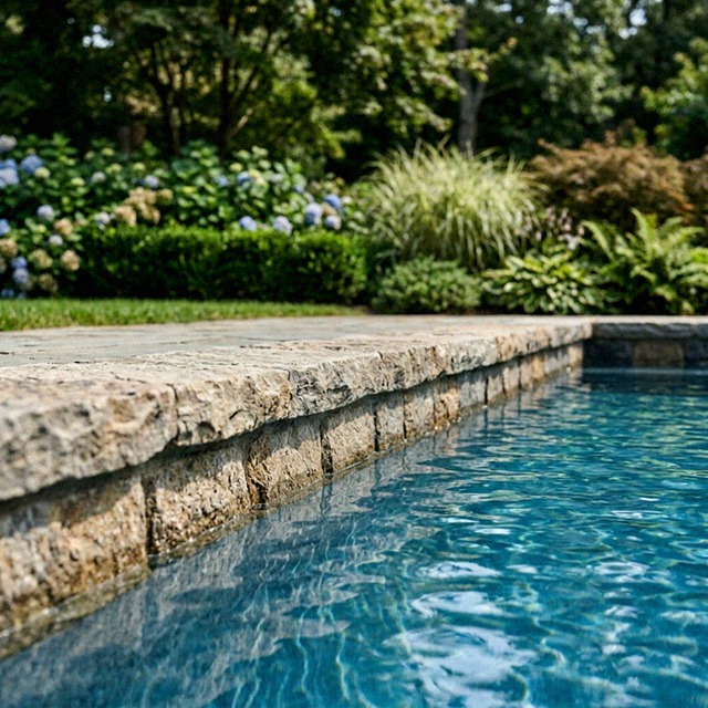 Close study of the water at the stone coping of a straight rectangular gunite pool, held at one constant level just below the coping